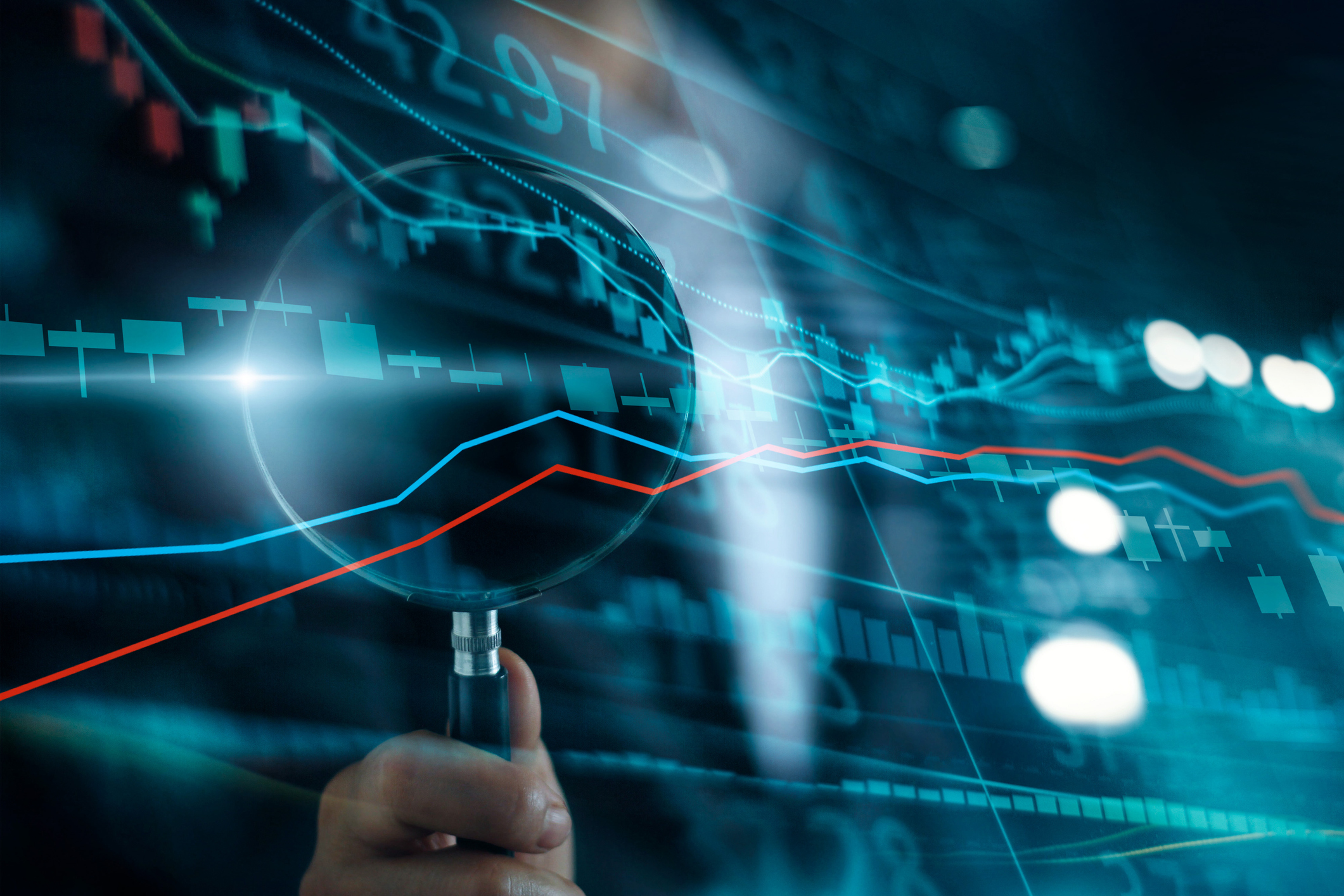 Magnifying glass focusing on digital financial graphs and charts