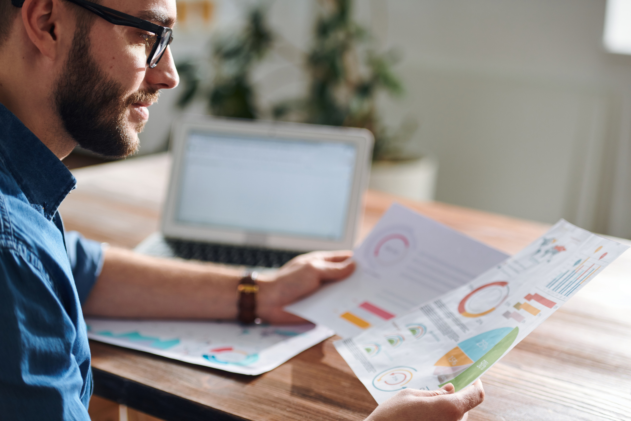 Person reviews charts at desk with open laptop