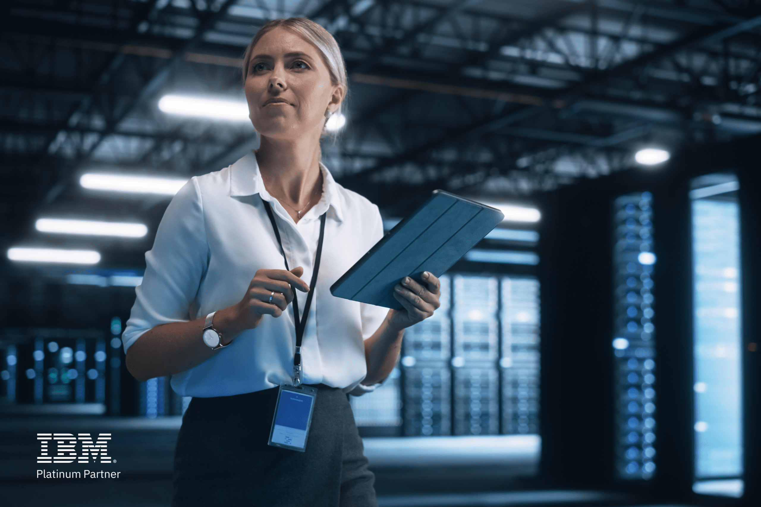 Woman in server room holding a tablet, wearing a lanyard. IBM Platinum Partner logo displayed