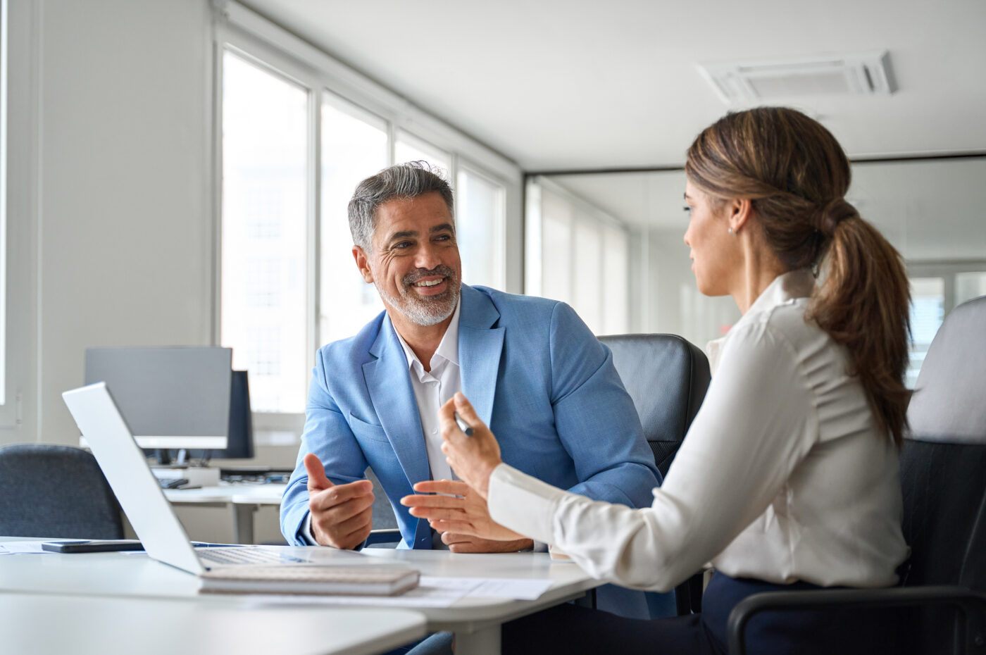 Man in blue suit smiling during office meeting conversation