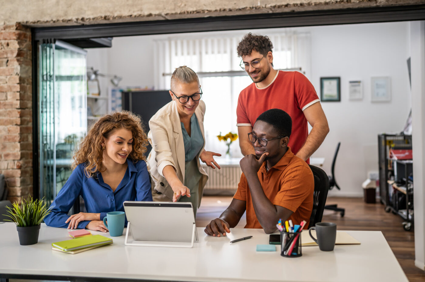Four colleagues discussing work at a table with a tablet