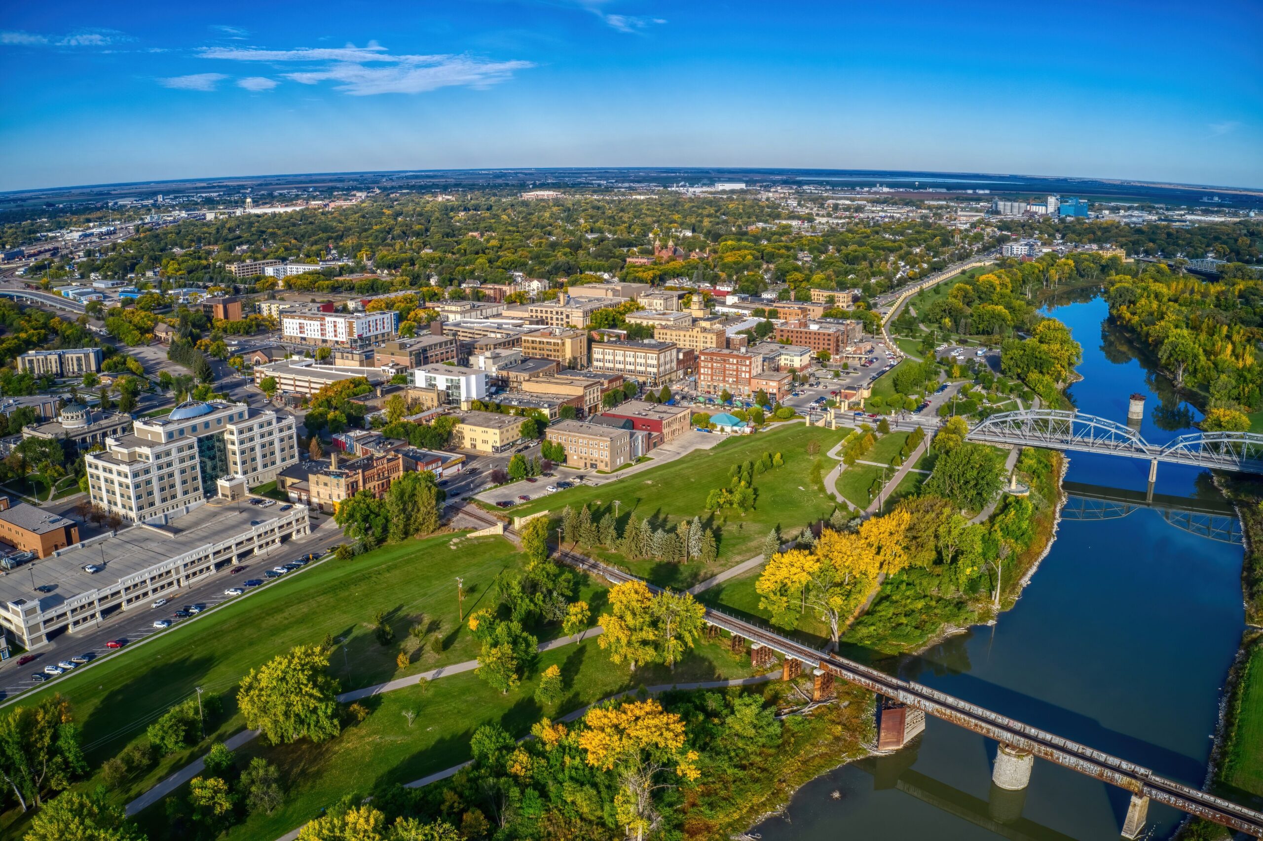 Aerial view of West Fargo cityscape, river, and green park spaces on a clear day